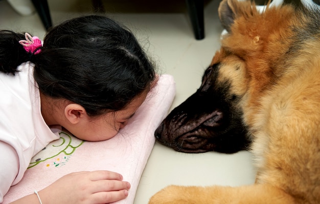 写真 犬と一緒にクッションの上に横たわっている子供の顔