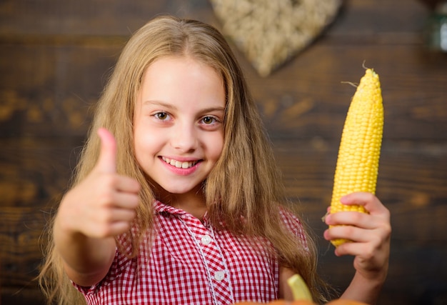 Kid farmer with harvest wooden background. Harvest festival concept. Girl kid at farm market with organic vegetables. Child little girl enjoy farm life. Organic gardening. Grow your own organic food.