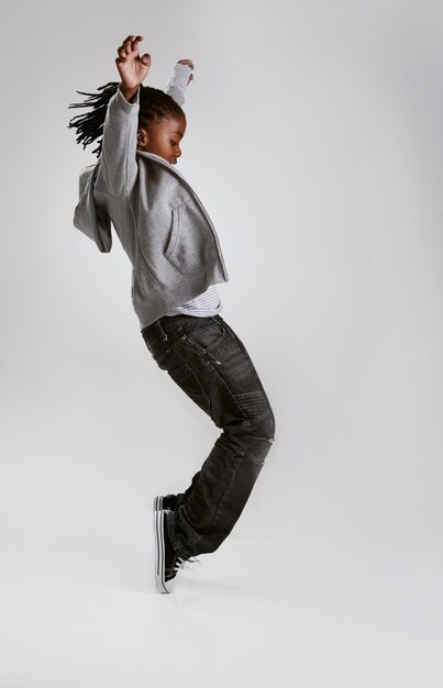 사진 아동 패션과 에너지와 함께 춤을 추는 스튜디오에서 회색 배경의 스트리트웨어에서 후디와 함께 아프리카 어린이와 멋진 십대 또는 캐주얼 스타일의 옷과 모형의 신발에 균형을 맞추는 댄서