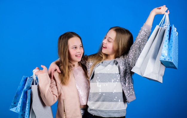 Kid fashion Happy children shop assistant with package Sisterhood and family savings on purchases Small girls with shopping bags Sales and discounts Little girl sisters online shopping