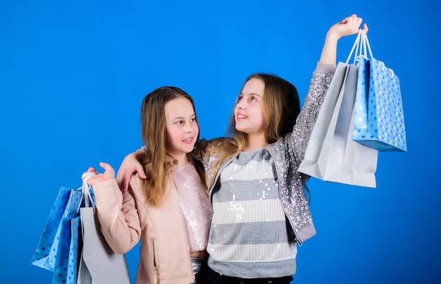 Kid fashion shop assistant with package Sales and discounts Sisterhood and family savings on purchases Small girls with shopping bags Happy children Little girl sisters online shopping