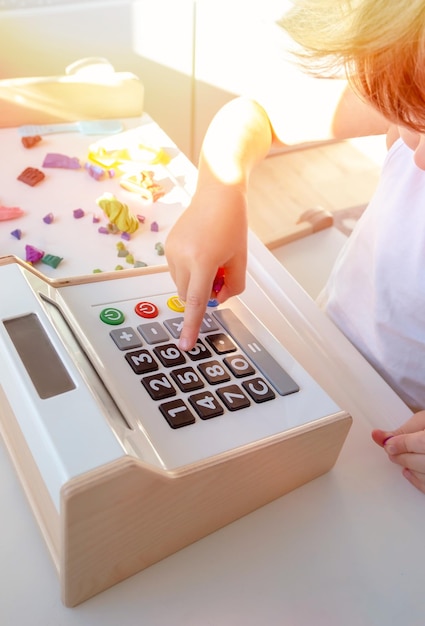 Kid fingers press to open cash drawer toys in the play area The concept of financial literacy