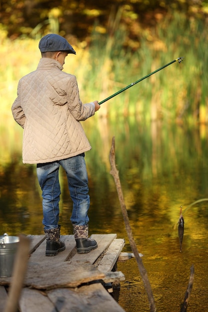 Kid fishing in a river sitting on a wood pontoon