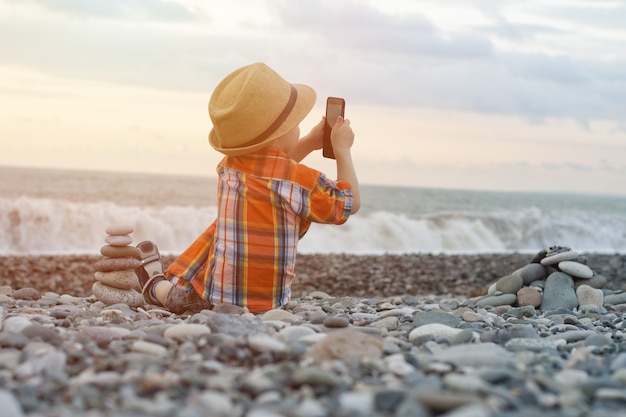 Kid foto's op de telefoon zittend op het strand