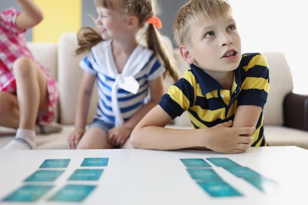 Kid friends playing card game on table at home involved in development