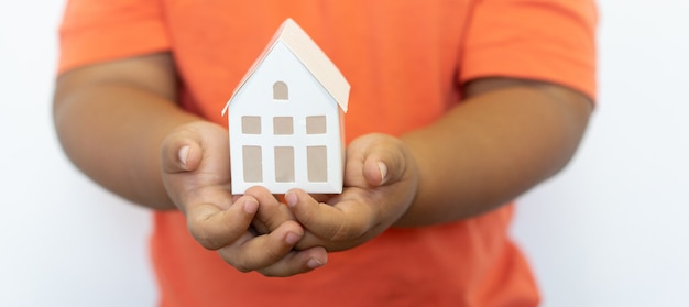 Foto kid gebaar hand met huis model voor familieverzekering en lening hypotheek concept