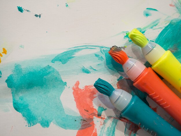 Kid gekleurde markeringen met penseelstreek lijnen op geschilderd wit papier achtergrond Macro selectieve focus
