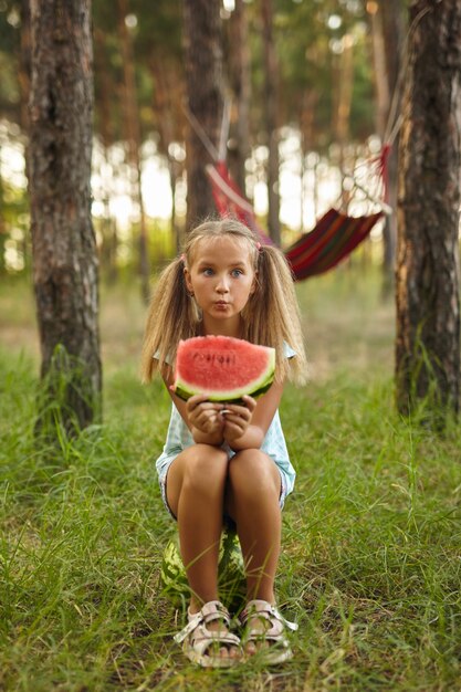 Kid girl eating watermelon in the garden.