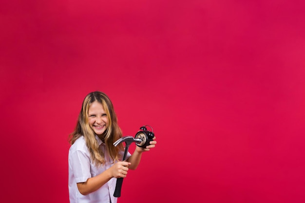 Kid girl holding hammer and alarm clock smiling with a happy and cool smile on face showing teeth