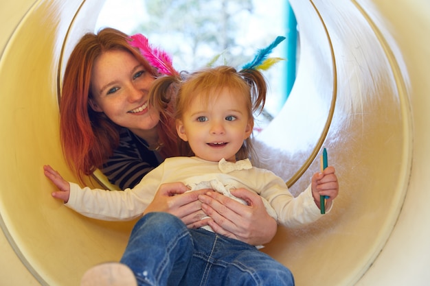 Kid girl and mother playing in the park slider