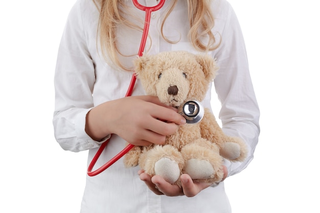 Kid girl playing doctor with plush toy as nursery