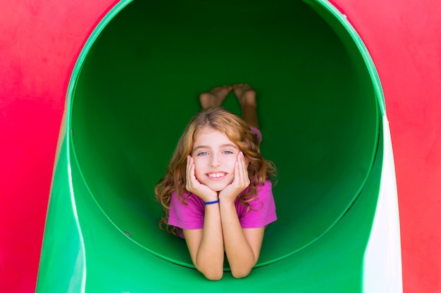 Ragazza del bambino che sorride nel parco giochi del parco rilassato