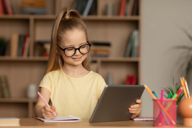 自宅でオンライン学習ノートを取るタブレットを使用して子供の女の子