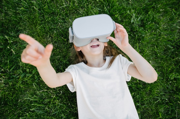 Ragazza del bambino utilizzando occhiali per realtà virtuale all'esterno