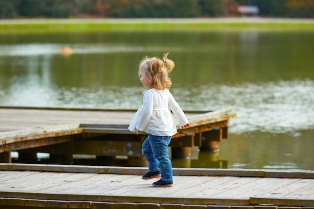 Kid girl walking in the lake pier