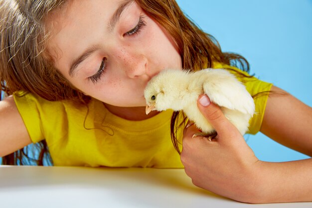 Kid girl with chicks playing on blue