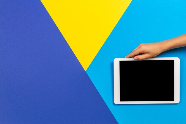 Kid hand met een witte tablet op een kleurrijke achtergrond