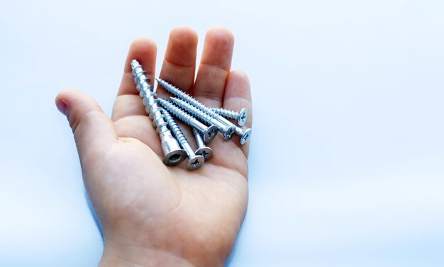 kid hand with screws light blue background boy holding metal bolts isolated mockup space for text