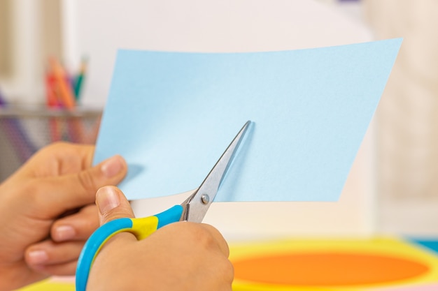 Kid handen snijden gekleurd papier met een schaar onderwijs leren papier ambachtelijke entertainment thuis