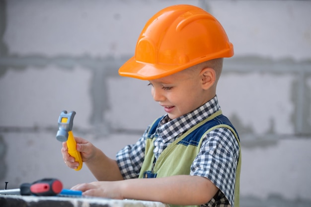 Kid in hard hat holding hammer little child helping with toy tools on construciton site kids with co