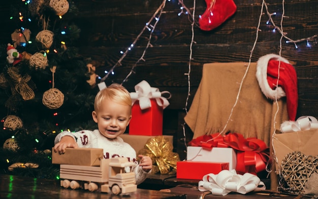 Bambino che si diverte vicino all'albero di natale al chiuso bambino gioioso che guarda l'obbiettivo a natale a casa l...