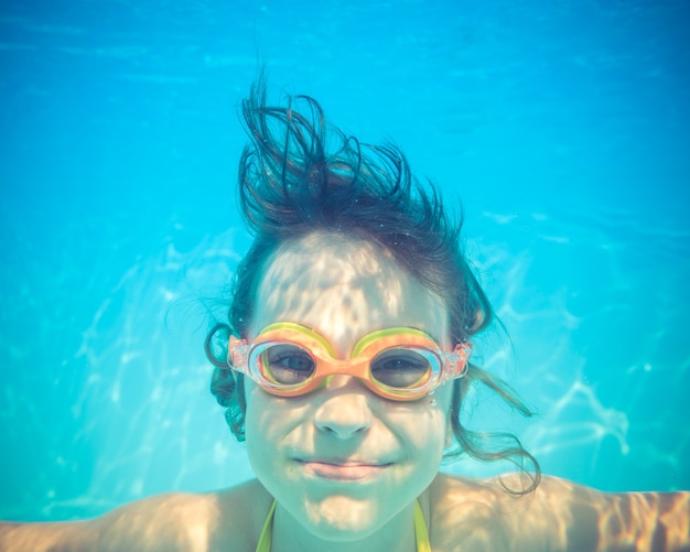 Kid having fun in swimming pool Underwater portrait of child Summer vacation