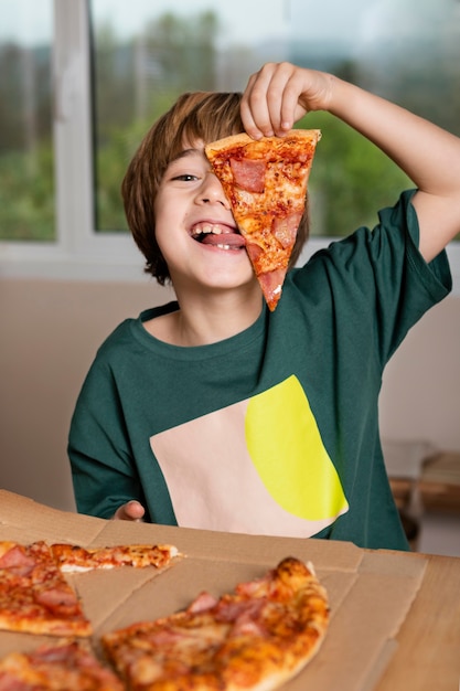 Photo kid having fun while eating pizza