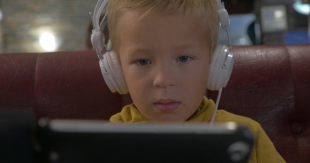 Kid in headphones watching cartoon on smart phone