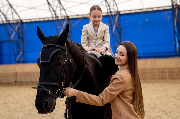 Kid in helmet on a horeback riding Cute girl learning horse riding