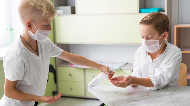 Photo kid helping his friend disinfecting