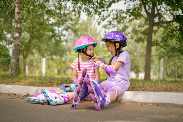 아이는 동생이 교외에서 함께 롤러 스케이팅을 할 때 보호 헬을 는 데 도움을 줍니다.