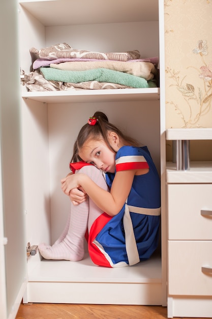 Photo kid hides in the cupboard.