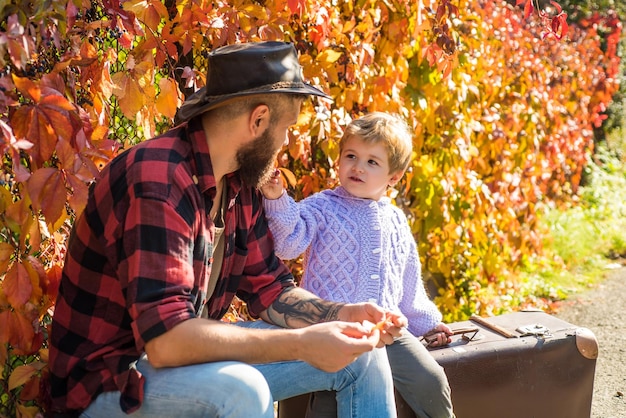 子供と彼の父親は秋の公園にいます 秋の公園で若い息子とひげのお父さんを持つ男