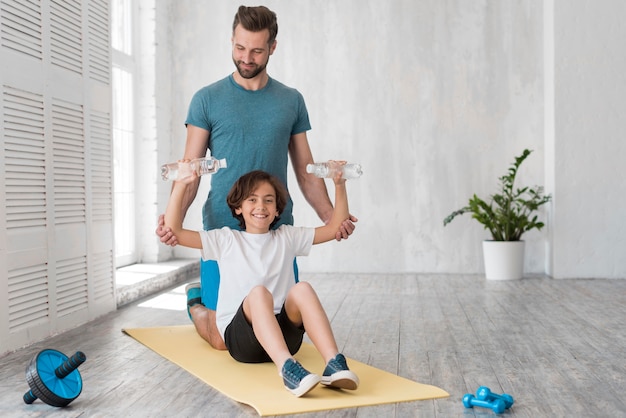 Photo kid and his father doing sport at home