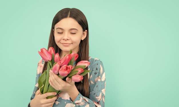 Kid hold flowers for 8 of march teen girl with spring bouquet on blue background