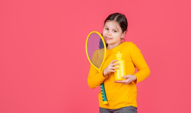 Фото Малыш держит теннисную ракетку и бутылку с водой на розовом фоне