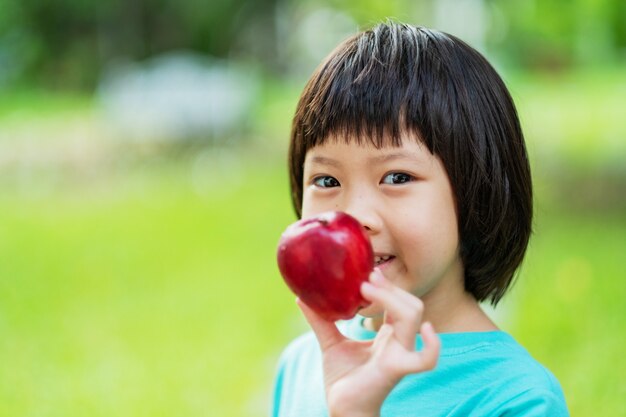 Bambino che tiene una mela con sfondo verde natura