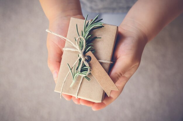 Foto kid holding scatola regalo con etichetta marrone