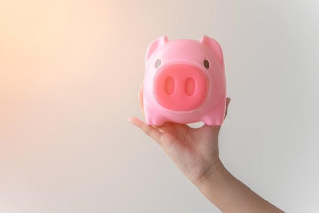 Kid holding her pink piggy bank concept of savings for future or education