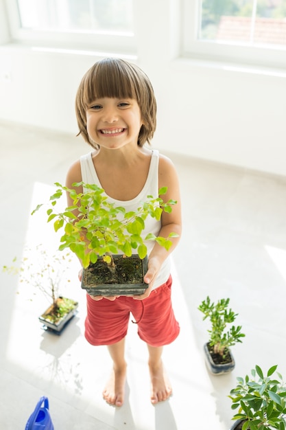 Kid holding plant growing organic herbs for cooking at home healthy lifestyle