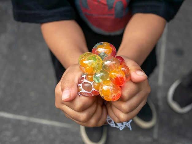 A kid holding and squeezing a colorful stress relief grape balls