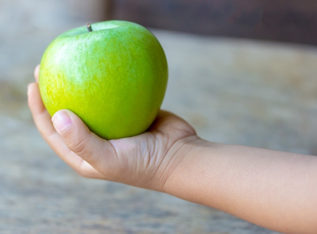 Il bambino tiene una mela verde