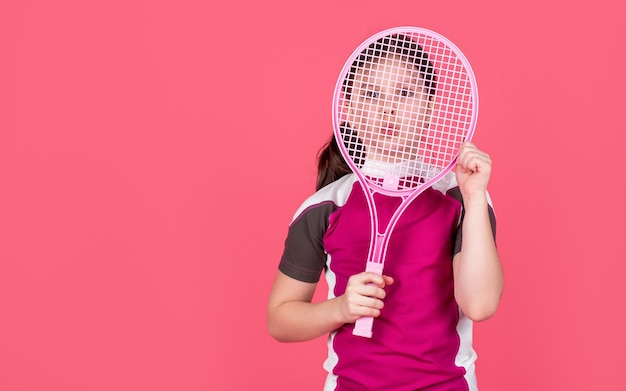 Kid houdt tennisracket op roze achtergrond met kopieerruimte