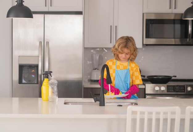 Kid housekeeper child washing and wiping dishes in kitchen american kid learning domestic chores at