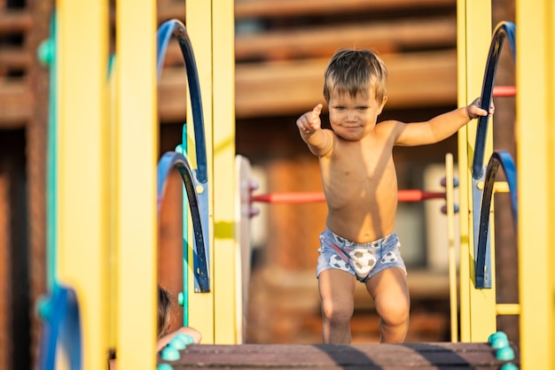 Kid in korte broek speelt op de speelplaats terwijl hij op straat loopt onder de zomerzon