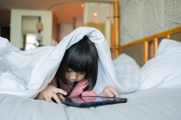 Kid is addicted to tablet, little girl playing smartphone, kid use telephone, watching cartoon
