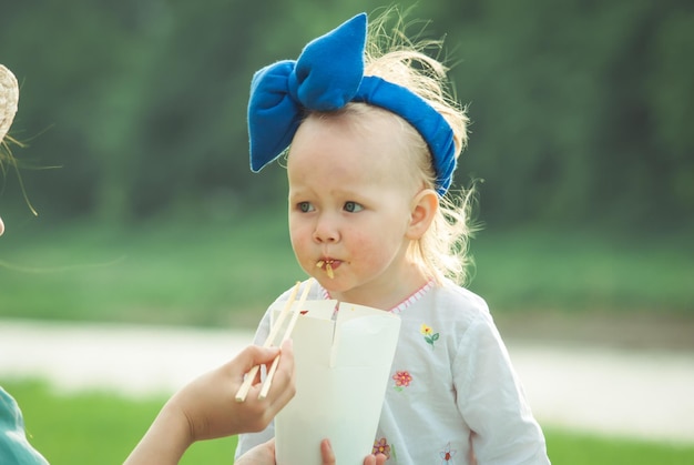 子供は日没時に自然の背景にタイ料理を食べています