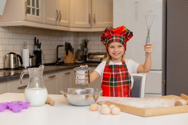 子供はお祝いの夕食を準備しています子供はふるい新年冬の概念を通して小麦粉をふるいにかけます