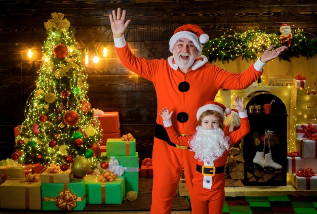 Kid jongen en vader in santa kostuum en baard kerst familievakanties en kindertijd concept weinig