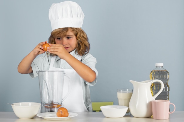 Kid jongen in koksmuts en schort koken maaltijd bereiden kleine kok met groenten in de keuken natuurlijk